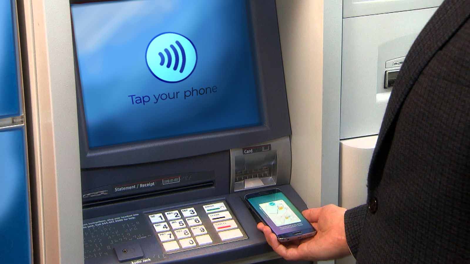person holding a mobile and tapping on the ATM machine to withdraw cash, image shows Cardless Banking