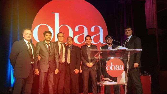 Group on men in suites smiling on stage after receiving award