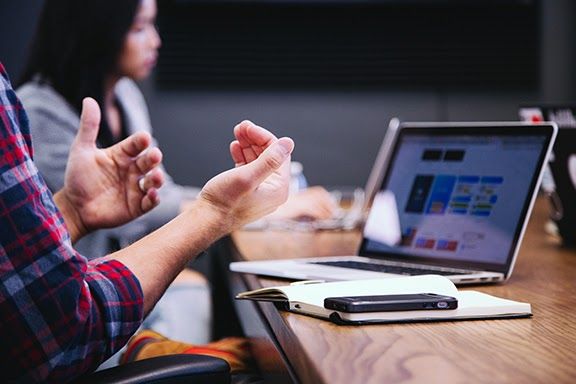 A close up of a persons hands as they speak in a meeting