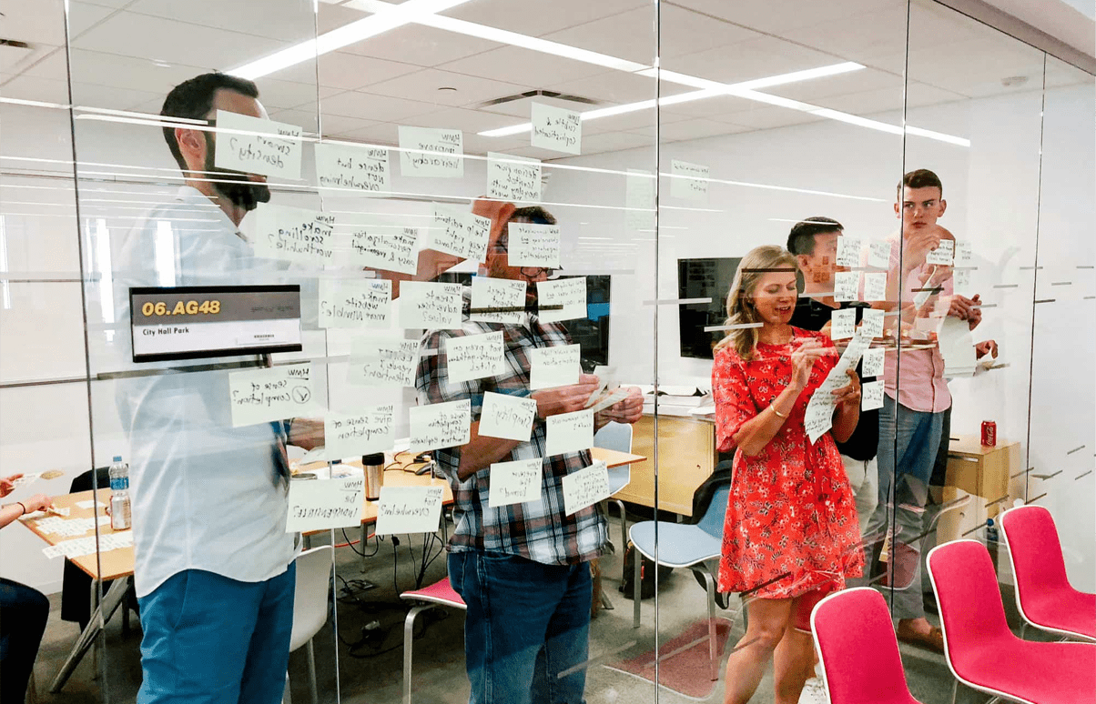 A team using a glass window to ideate with various sticky notes