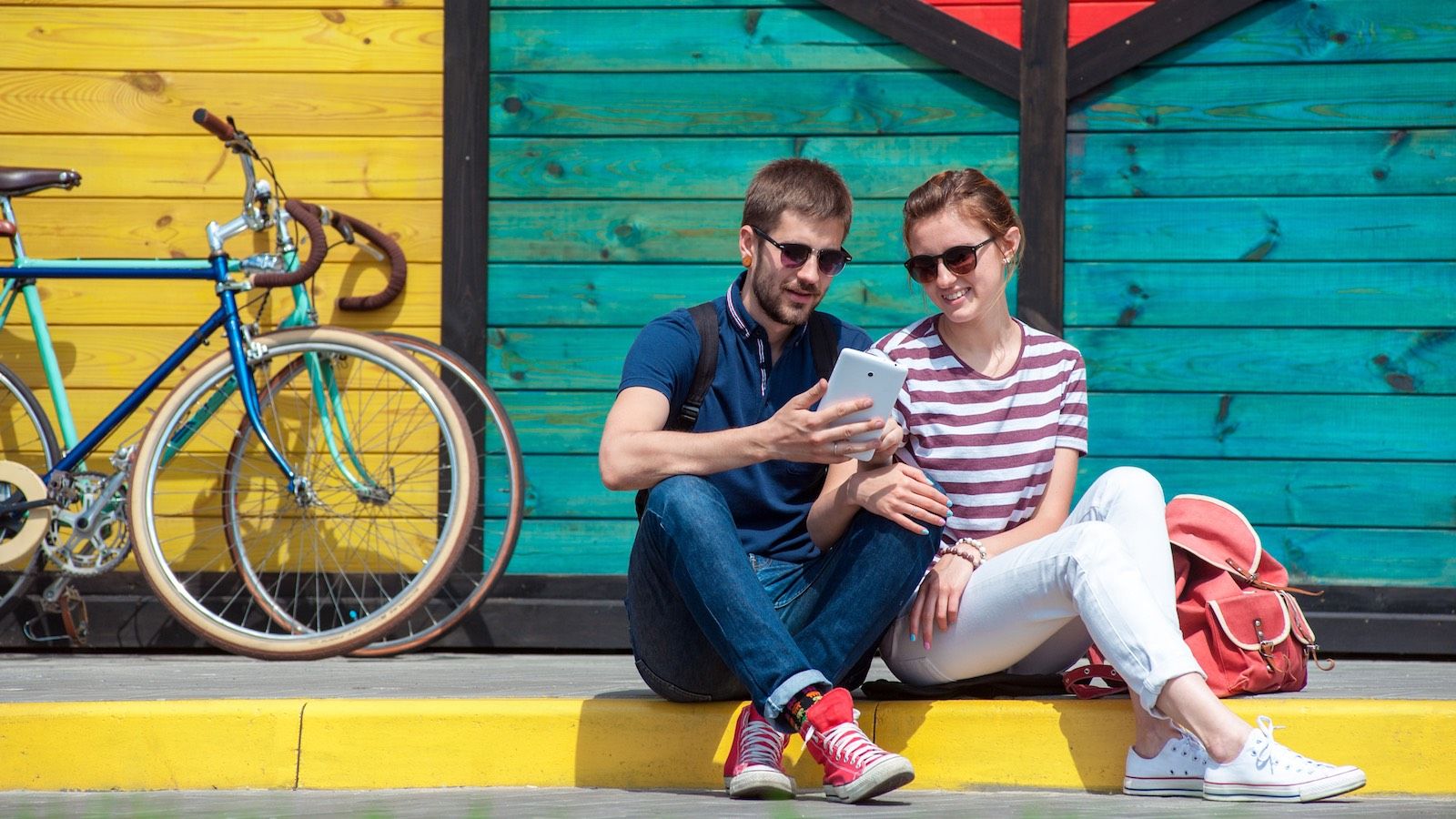 Couple looking at phone sitting on curb